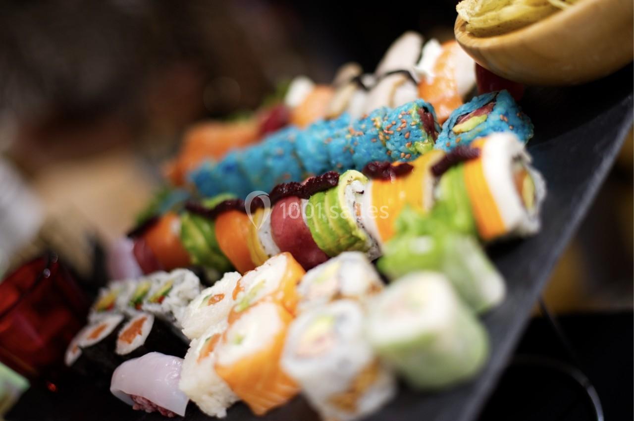 Assortiment coloré de sushis et makis variés disposés sur un plateau noir.