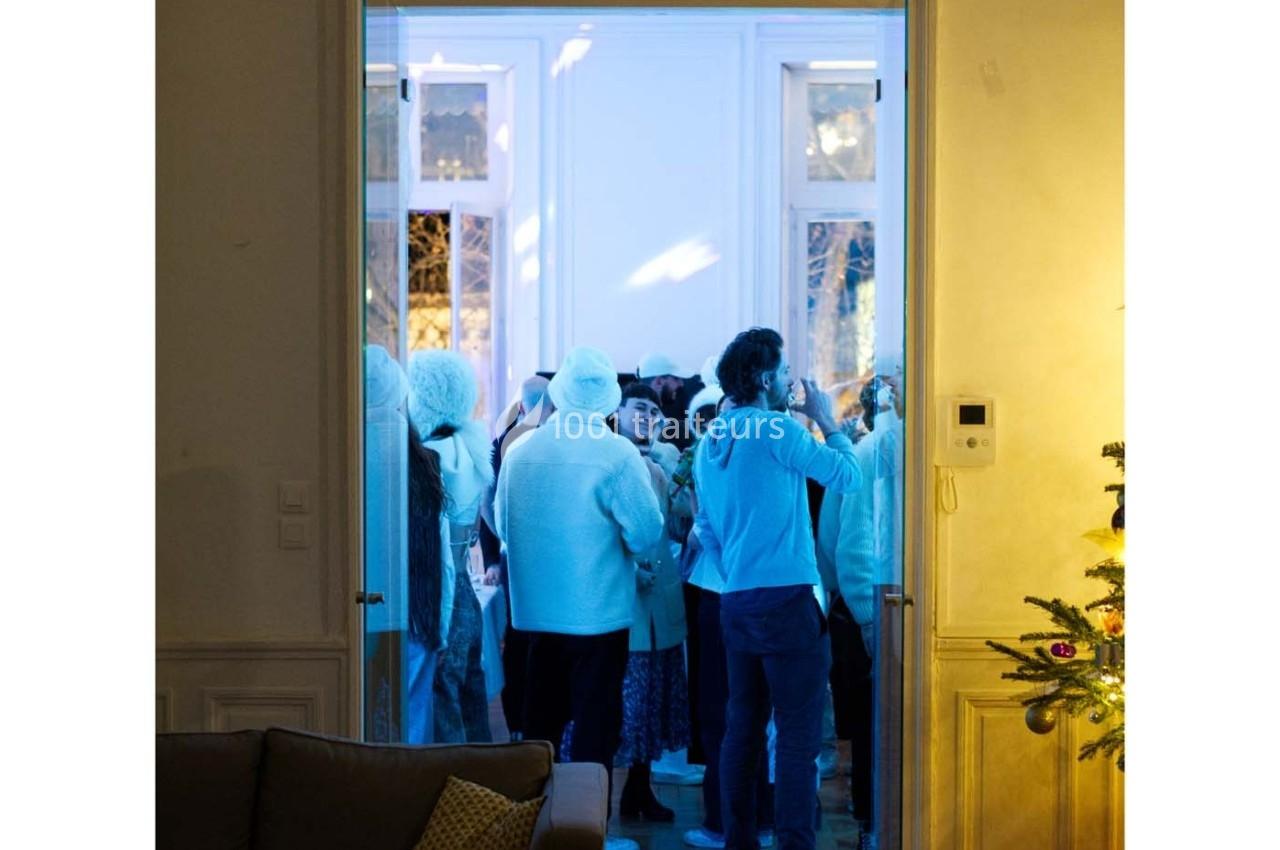 Groupe de personnes en vêtements d'hiver rassemblées dans une pièce éclairée par une lumière bleutée.