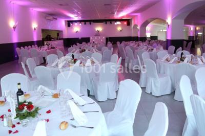 Table dressée avec nappes blanches, verres et couverts, vue sur une terrasse avec piscine et chaises en arrière-plan.