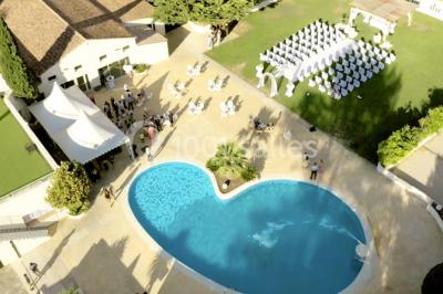 Table dressée avec nappes blanches, verres et couverts, vue sur une terrasse avec piscine et chaises en arrière-plan.