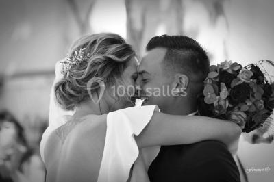 Table dressée avec nappes blanches, verres et couverts, vue sur une terrasse avec piscine et chaises en arrière-plan.