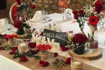 Table dressée avec nappes blanches, verres et couverts, vue sur une terrasse avec piscine et chaises en arrière-plan.
