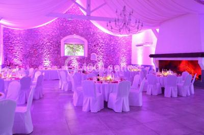 Table dressée avec nappes blanches, verres et couverts, vue sur une terrasse avec piscine et chaises en arrière-plan.