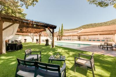 Table dressée avec nappes blanches, verres et couverts, vue sur une terrasse avec piscine et chaises en arrière-plan.