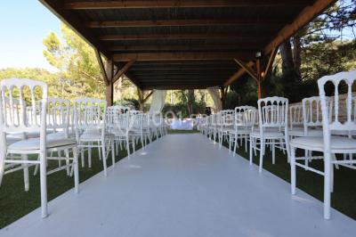 Table dressée avec nappes blanches, verres et couverts, vue sur une terrasse avec piscine et chaises en arrière-plan.