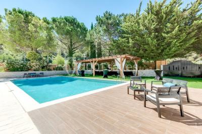 Table dressée avec nappes blanches, verres et couverts, vue sur une terrasse avec piscine et chaises en arrière-plan.