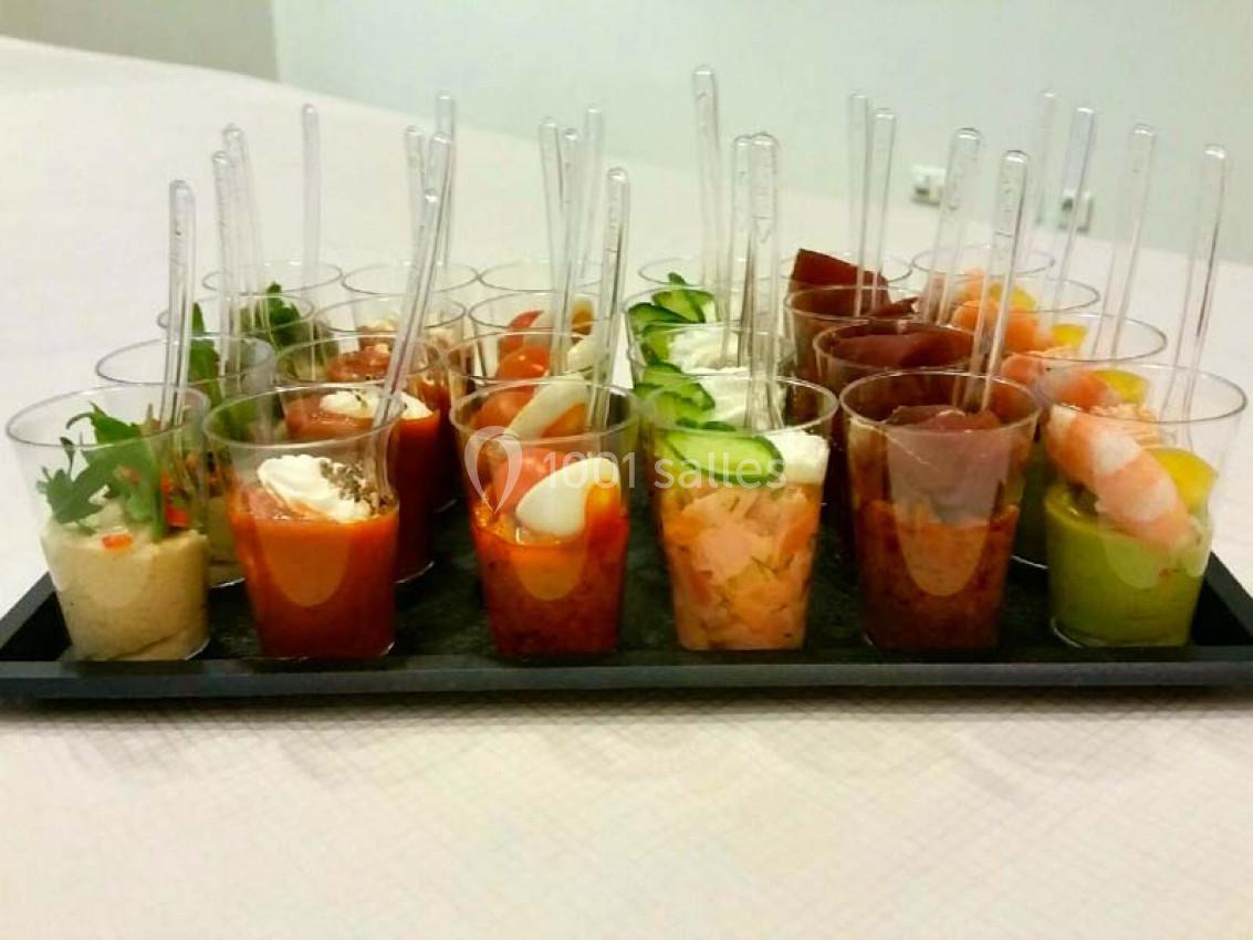 Plateau de verrines variées contenant des ingrédients colorés comme légumes, crevettes et sauces, avec cuillères.