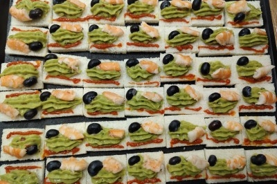 Plateau de canapés variés sur pain blanc, garnis de légumes, herbes fraîches et condiments colorés.