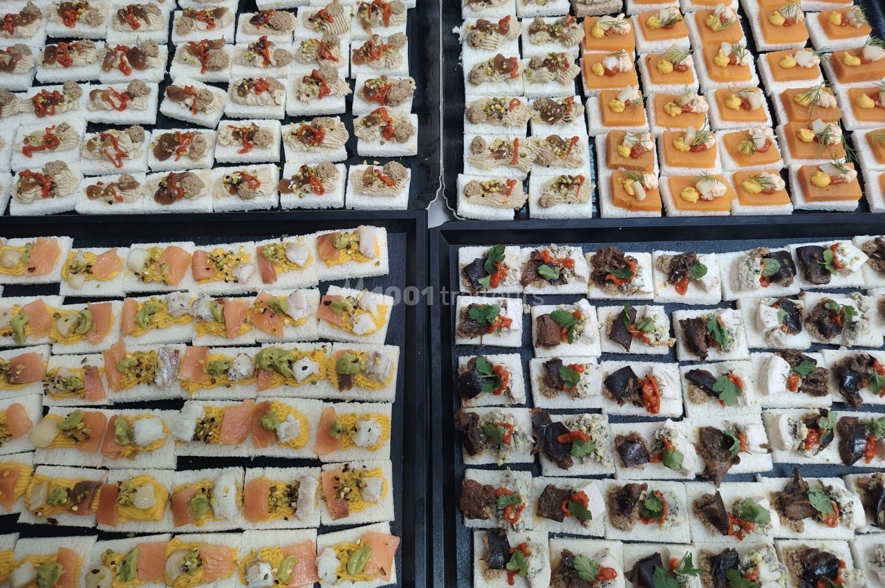 Plateaux de canapés variés avec garnitures colorées, incluant saumon, légumes, viandes et condiments.