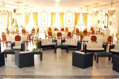 Chambre classique avec lit double, mobilier en bois, rideaux dorés et lumière naturelle entrant par une fenêtre.