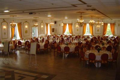 Chambre classique avec lit double, mobilier en bois, rideaux dorés et lumière naturelle entrant par une fenêtre.