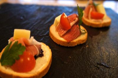 Tranches de pain garnies de jambon, fromage, tomate cerise et persil, présentées sur une ardoise noire.