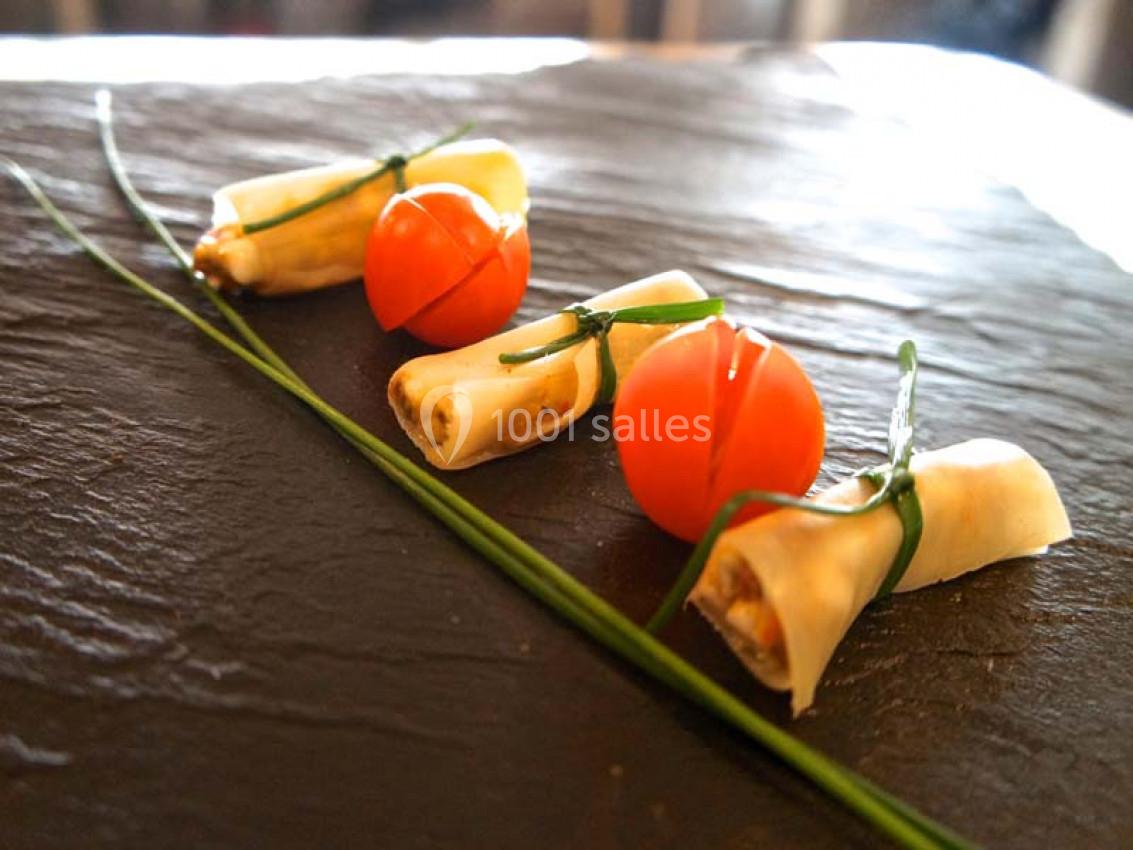 Bouchées apéritives composées de tomates cerises et de fromage roulé, attachées avec des brins de ciboulette.