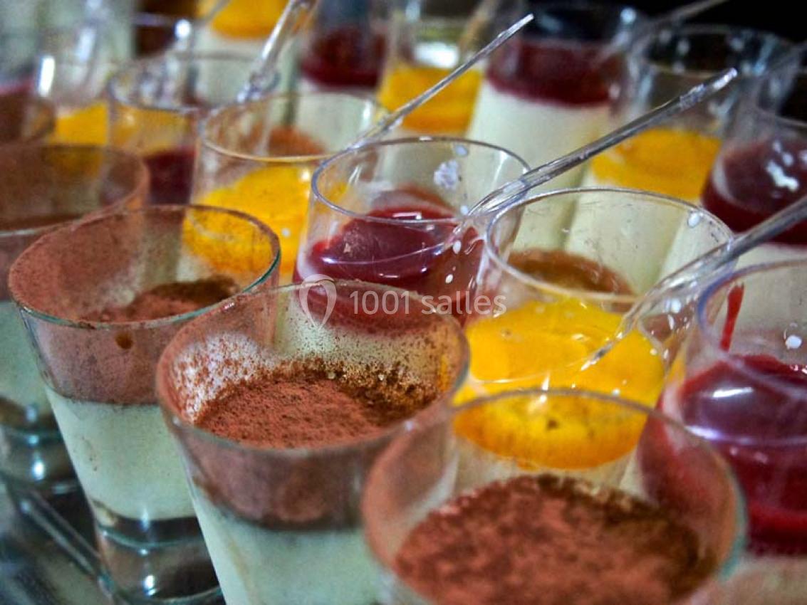 Verrines de desserts variés avec couches de crème, cacao, gelée rouge et jaune, présentées avec des cuillères.