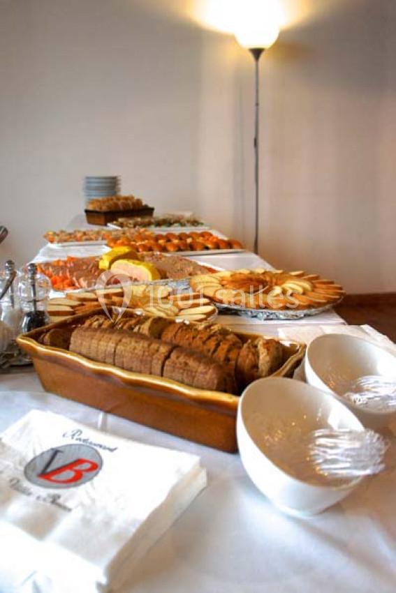 Table dressée avec des plats variés, comprenant du pain tranché, des biscuits et des fruits, éclairée par une lampe.