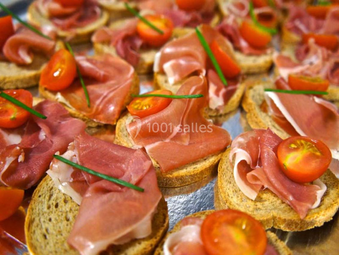 Tranches de jambon cru, tomates cerises et brins de ciboulette disposés sur des toasts.