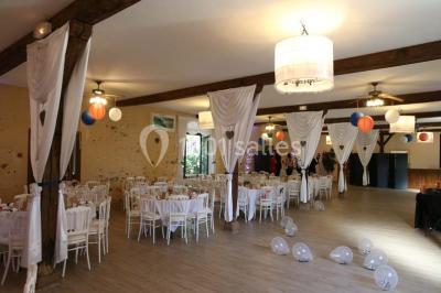 Table dressée en extérieur avec nappes blanches, boissons et verres, entourée de buissons fleuris d'hortensias.