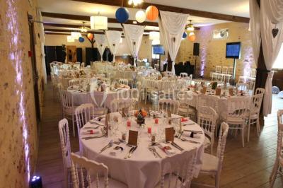 Table dressée en extérieur avec nappes blanches, boissons et verres, entourée de buissons fleuris d'hortensias.