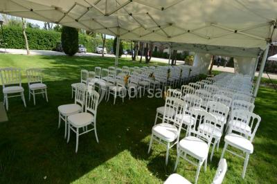 Table dressée en extérieur avec nappes blanches, boissons et verres, entourée de buissons fleuris d'hortensias.