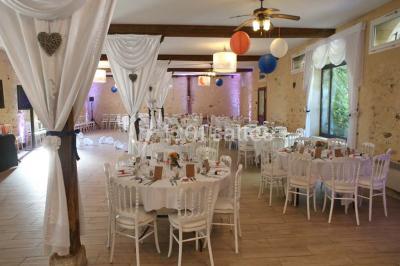 Table dressée en extérieur avec nappes blanches, boissons et verres, entourée de buissons fleuris d'hortensias.
