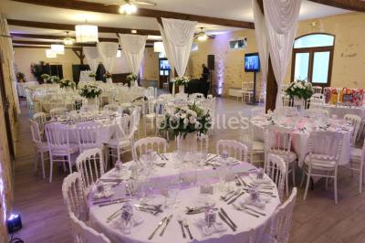 Table dressée en extérieur avec nappes blanches, boissons et verres, entourée de buissons fleuris d'hortensias.