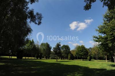 Table dressée en extérieur avec nappes blanches, boissons et verres, entourée de buissons fleuris d'hortensias.