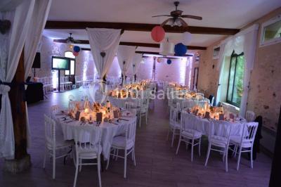 Table dressée en extérieur avec nappes blanches, boissons et verres, entourée de buissons fleuris d'hortensias.