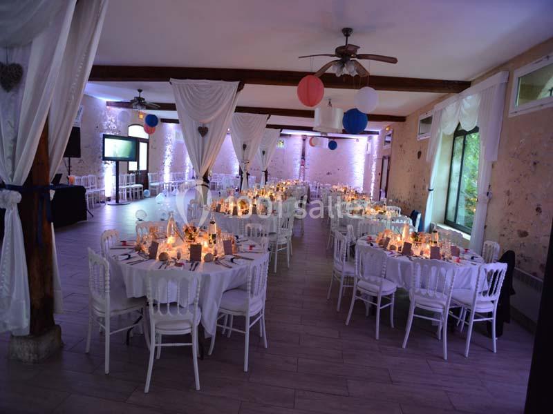 Salle de réception décorée avec des tables dressées, éclairage tamisé et suspensions colorées au plafond.