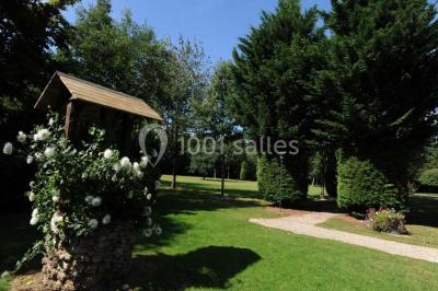 Table dressée en extérieur avec nappes blanches, boissons et verres, entourée de buissons fleuris d'hortensias.