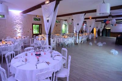 Table dressée en extérieur avec nappes blanches, boissons et verres, entourée de buissons fleuris d'hortensias.