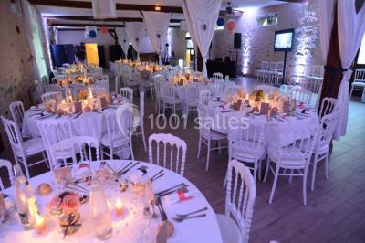 Table dressée en extérieur avec nappes blanches, boissons et verres, entourée de buissons fleuris d'hortensias.