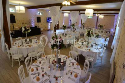 Table dressée en extérieur avec nappes blanches, boissons et verres, entourée de buissons fleuris d'hortensias.