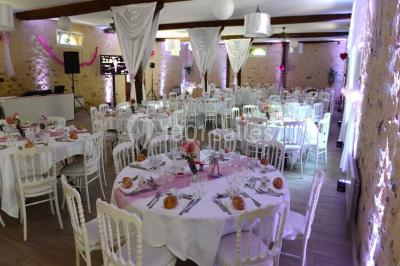 Table dressée en extérieur avec nappes blanches, boissons et verres, entourée de buissons fleuris d'hortensias.