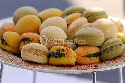 Table dressée en extérieur avec nappes blanches, boissons et verres, entourée de buissons fleuris d'hortensias.