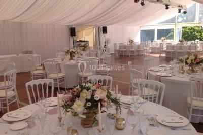Table élégamment dressée avec chandeliers, verres et décorations sous un plafond illuminé de guirlandes lumineuses.