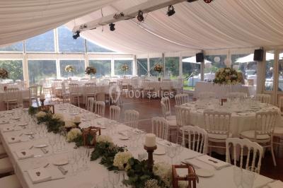 Table élégamment dressée avec chandeliers, verres et décorations sous un plafond illuminé de guirlandes lumineuses.
