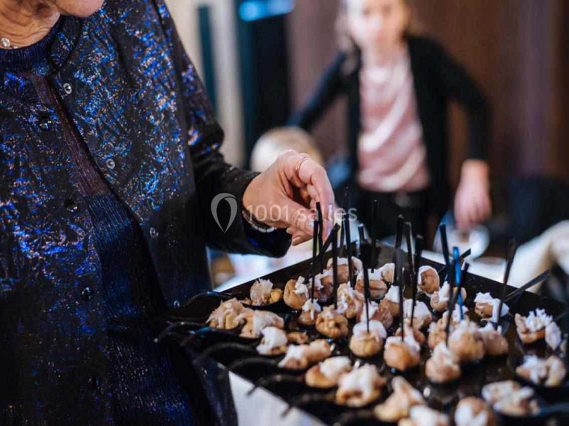 Plateau de bouchées apéritives servies sur des pics, tenu par une personne lors d'un événement.