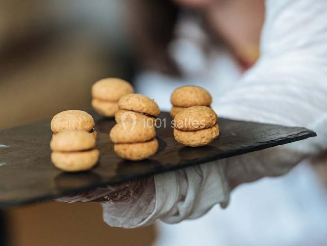 Assortiment de petits biscuits ronds garnis, présentés sur un plateau en ardoise.