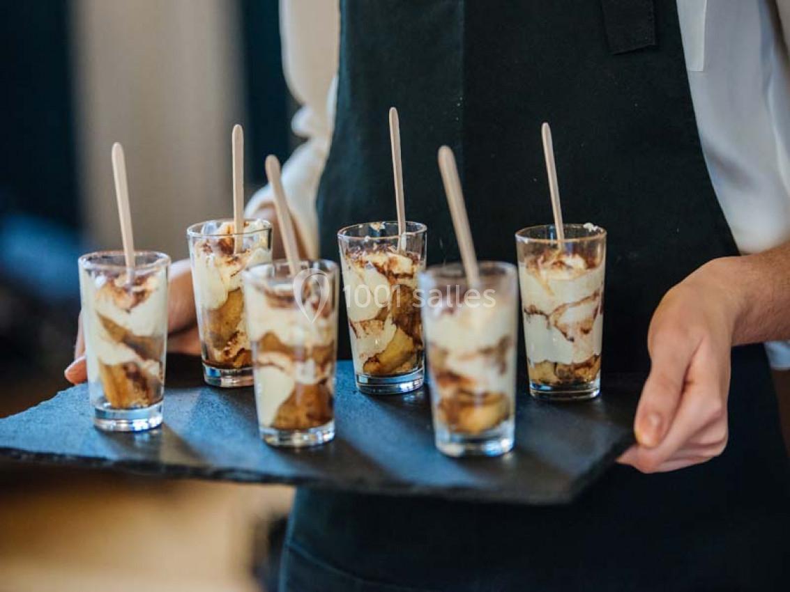 Traiteur Paris (Paris) - Profumo Traiteur Italien #22 Six verrines de tiramisu sont présentées sur un plateau noir, tenues par une personne en tablier.