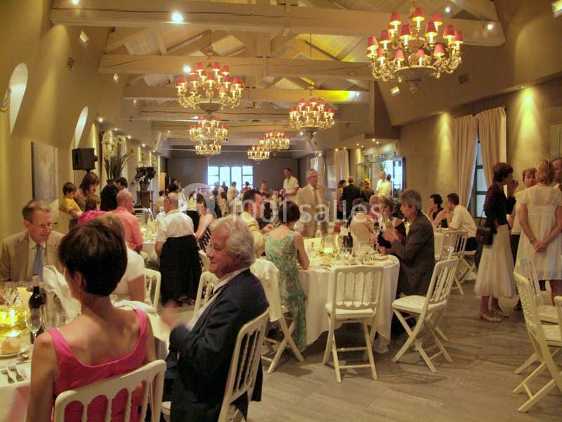 Location salle Sorgues (Vaucluse) - Château La Tour Vaucros #4 Salle de réception avec des invités assis à des tables rondes, éclairée par des lustres et une lumière chaleureuse.
