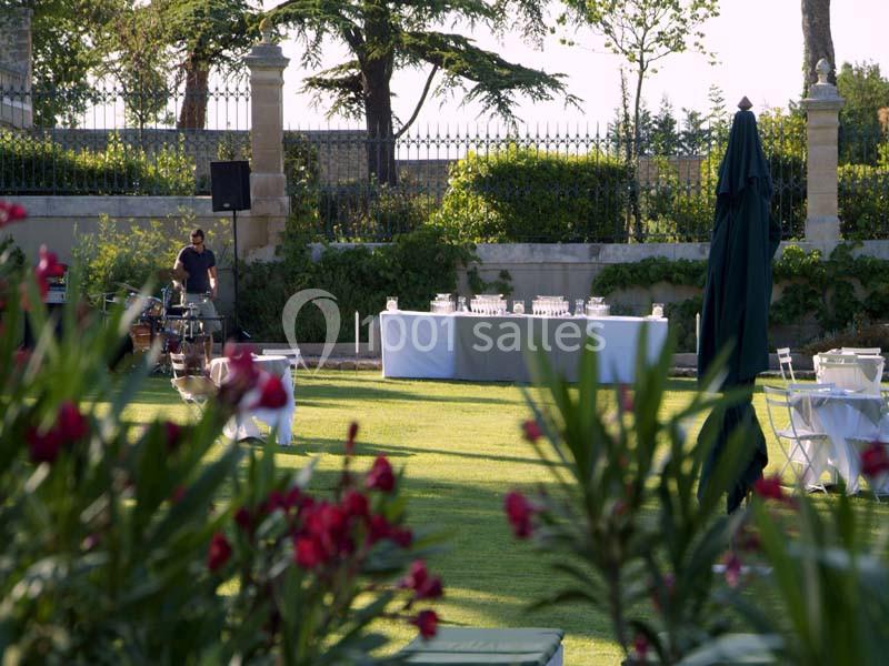 Location salle Sorgues (Vaucluse) - Château La Tour Vaucros #6 Jardin aménagé avec tables, chaises et buffet en arrière-plan, entouré de verdure et de fleurs au premier plan.