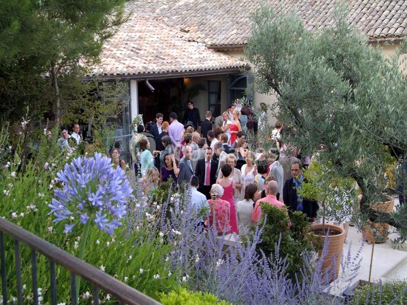 Location salle Sorgues (Vaucluse) - Château La Tour Vaucros #19 Groupe de personnes rassemblées dans un jardin fleuri près d'une maison au toit de tuiles.