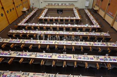 Salle de réunion lumineuse avec table ovale, chaises, paperboard et vue sur la Tour Eiffel à travers de grandes fenêtres.