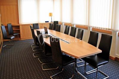 Salle de réunion lumineuse avec table ovale, chaises, paperboard et vue sur la Tour Eiffel à travers de grandes fenêtres.