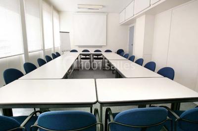 Salle de réunion lumineuse avec table ovale, chaises, paperboard et vue sur la Tour Eiffel à travers de grandes fenêtres.