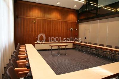 Salle de réunion lumineuse avec table ovale, chaises, paperboard et vue sur la Tour Eiffel à travers de grandes fenêtres.