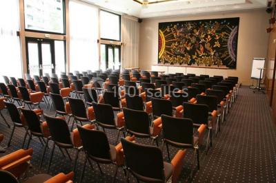 Salle de réunion lumineuse avec table ovale, chaises, paperboard et vue sur la Tour Eiffel à travers de grandes fenêtres.