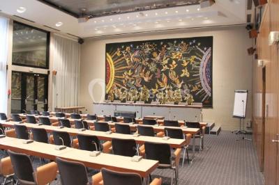 Salle de réunion lumineuse avec table ovale, chaises, paperboard et vue sur la Tour Eiffel à travers de grandes fenêtres.