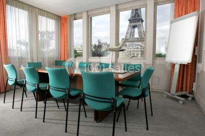 Salle de réunion lumineuse avec table ovale, chaises, paperboard et vue sur la Tour Eiffel à travers de grandes fenêtres.