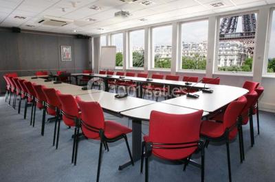 Salle de réunion lumineuse avec table ovale, chaises, paperboard et vue sur la Tour Eiffel à travers de grandes fenêtres.